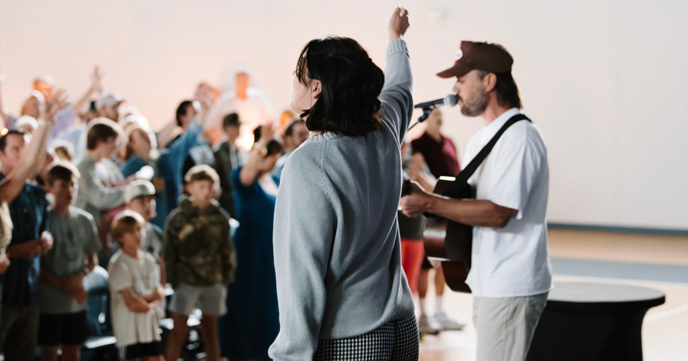 Leaders leading a room of kids in worship during Large Group