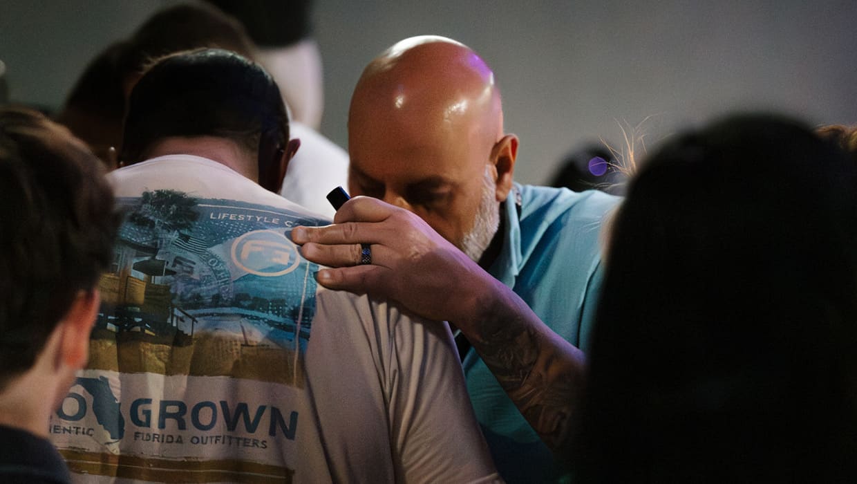 A care team member praying over a man during a service