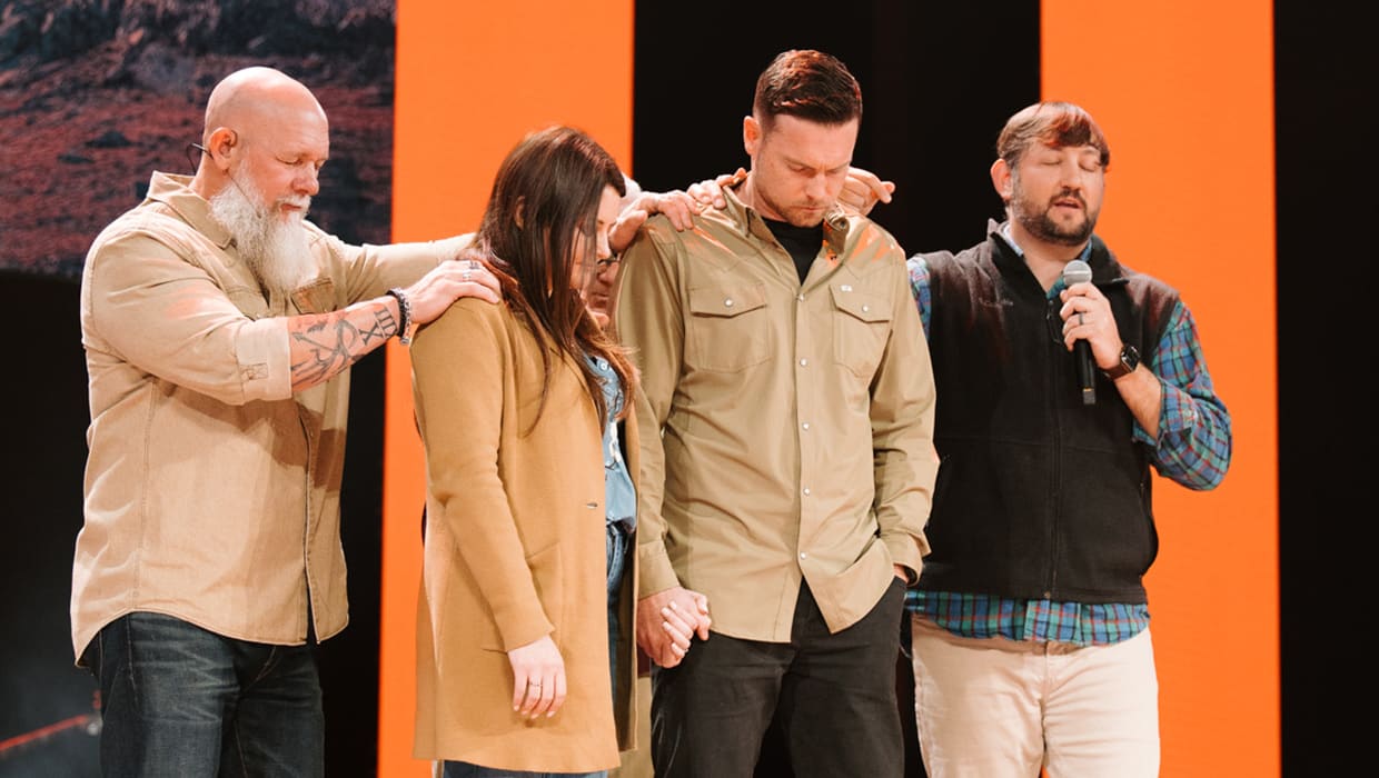 Pastors praying over a church planting couple on stage