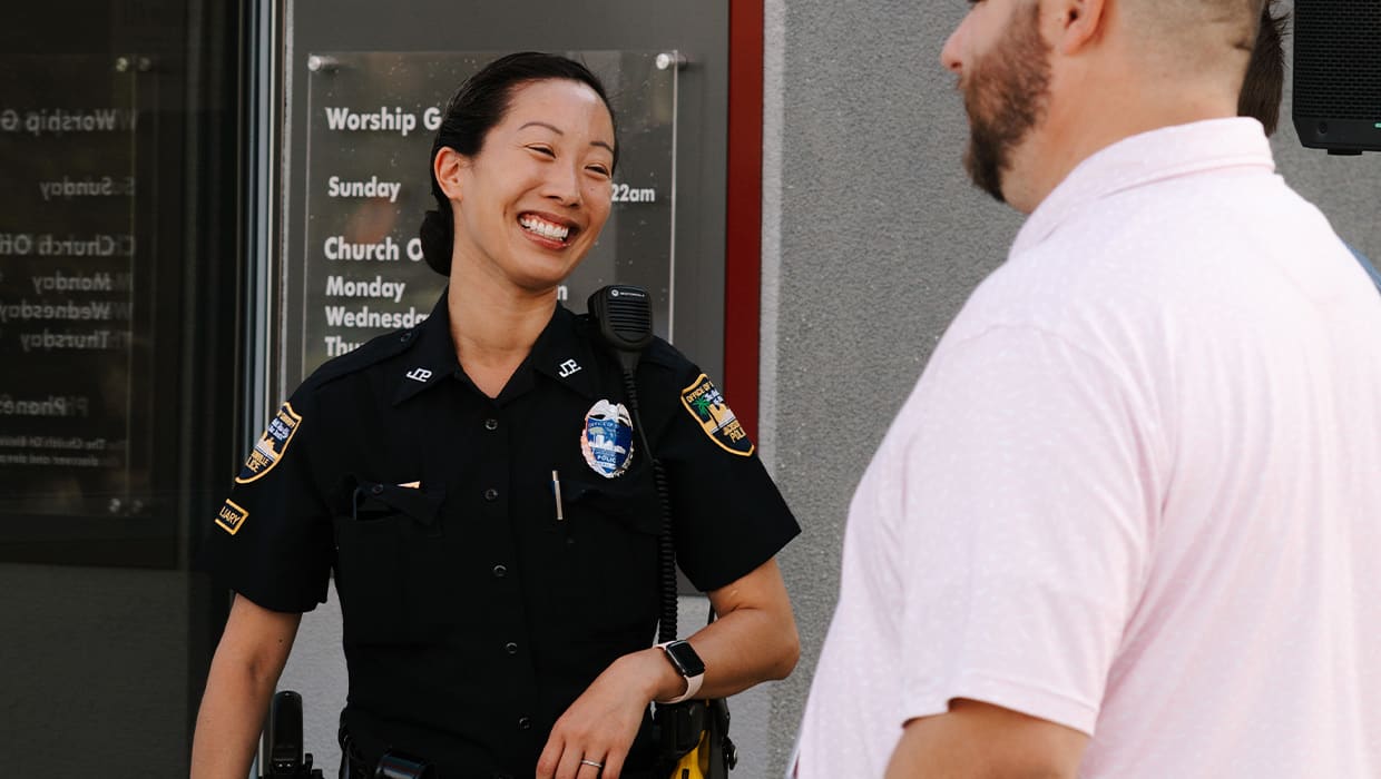 A police officer laughing with an Eleven22 staff member outside a campus