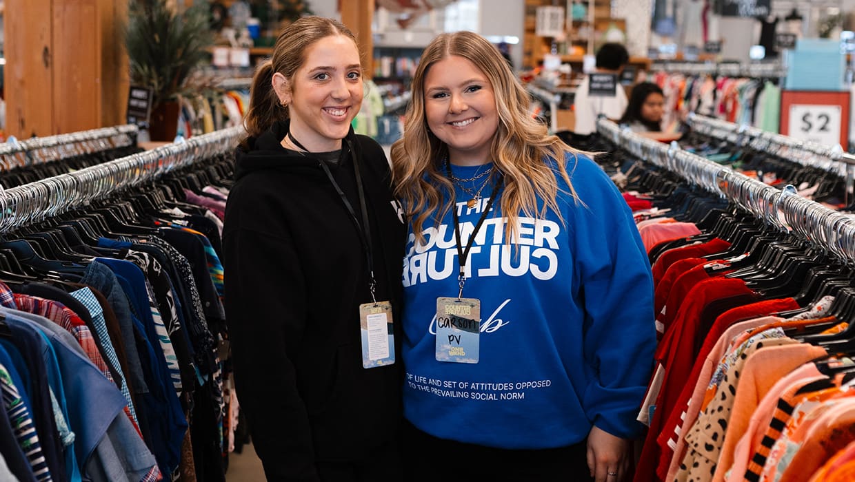 Two volunteers standing between clothing racks at Hope's Closet