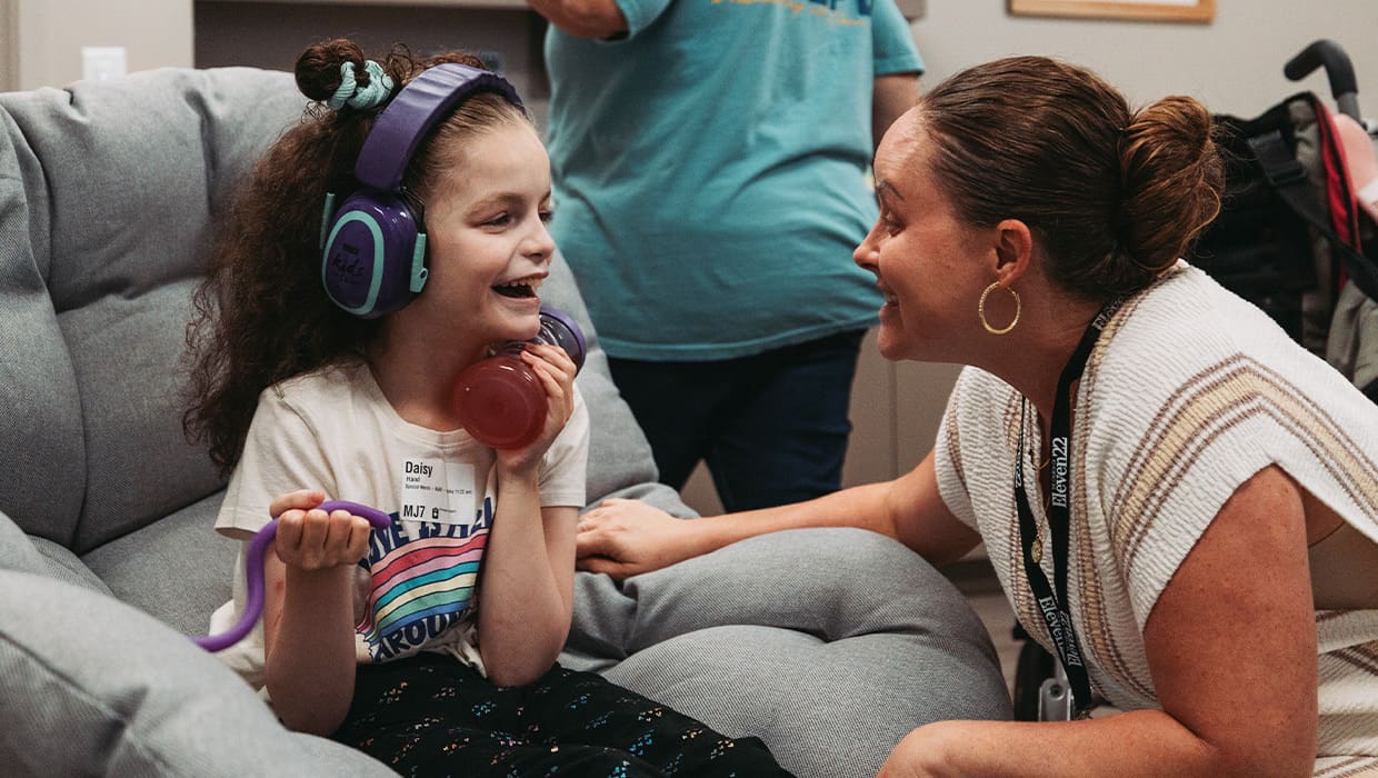 A special needs buddy laughing with a child wearing headphones