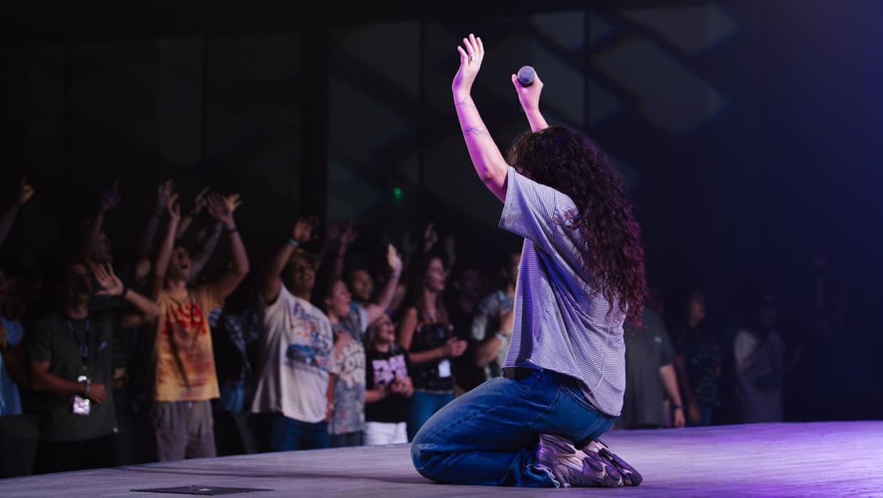 A worship leader kneeling on stage during an Eleven22 worship night