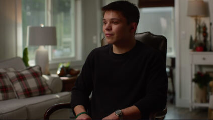 Young man sitting in a chair in a cozy living room, reflecting on personal experiences, emphasizing themes of faith and growth relevant to the sermon series 'Stand Firm & Act Like Men'.