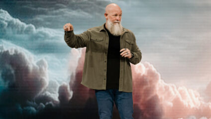 Pastor Joby Martin speaking on stage with a dramatic cloud backdrop, emphasizing spiritual teachings at The Church of Eleven22.
